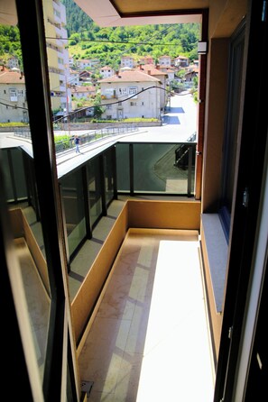 A balcony with a view of a residential area, a glass railing, and a tiled floor. - Nature Heals by Todoroff (Devin)