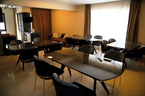 Una habitación de hotel moderna con zona de comedor, sofá y televisor.