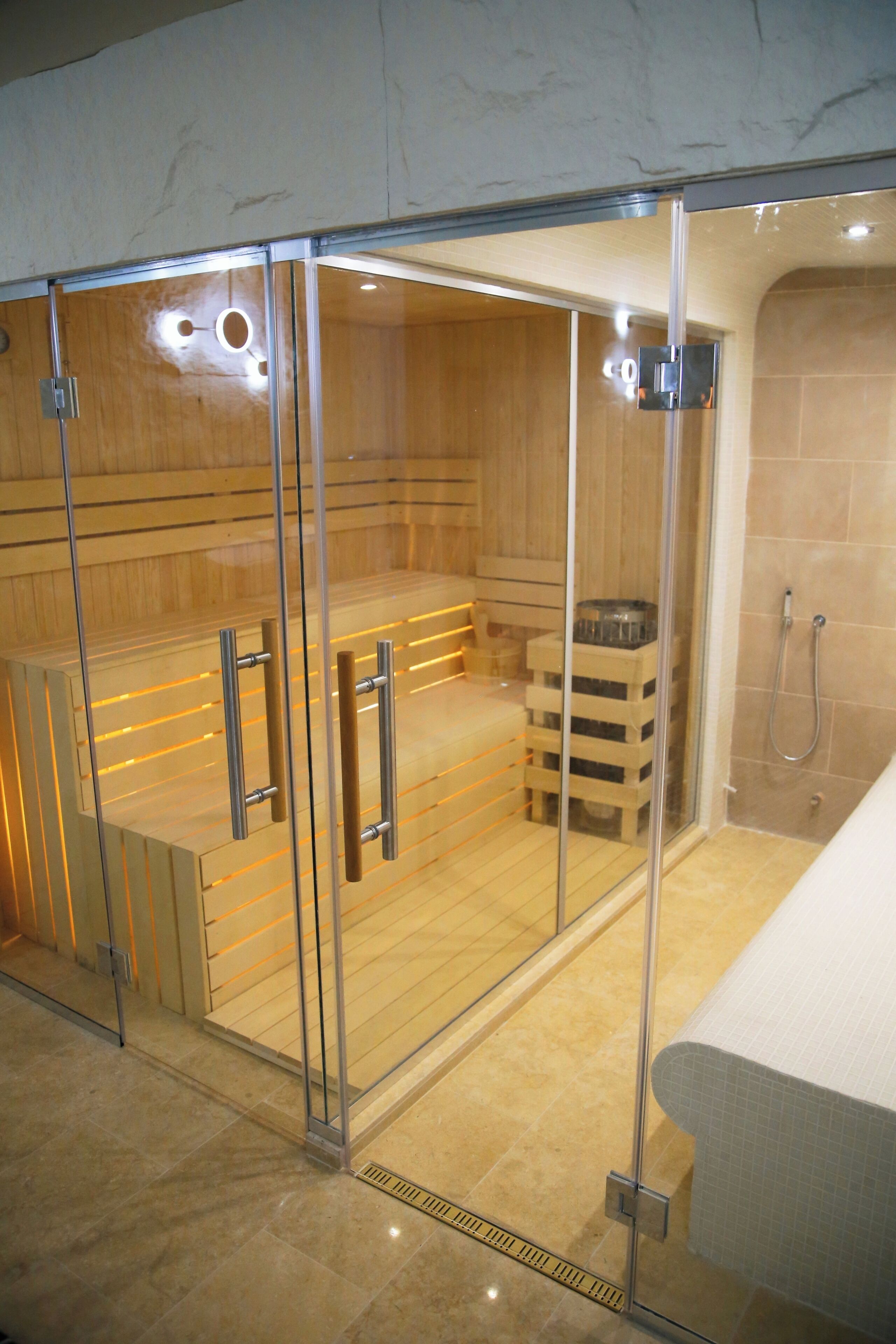 Un sauna doté de portes en verre, de bancs en bois et d’un espace douche.