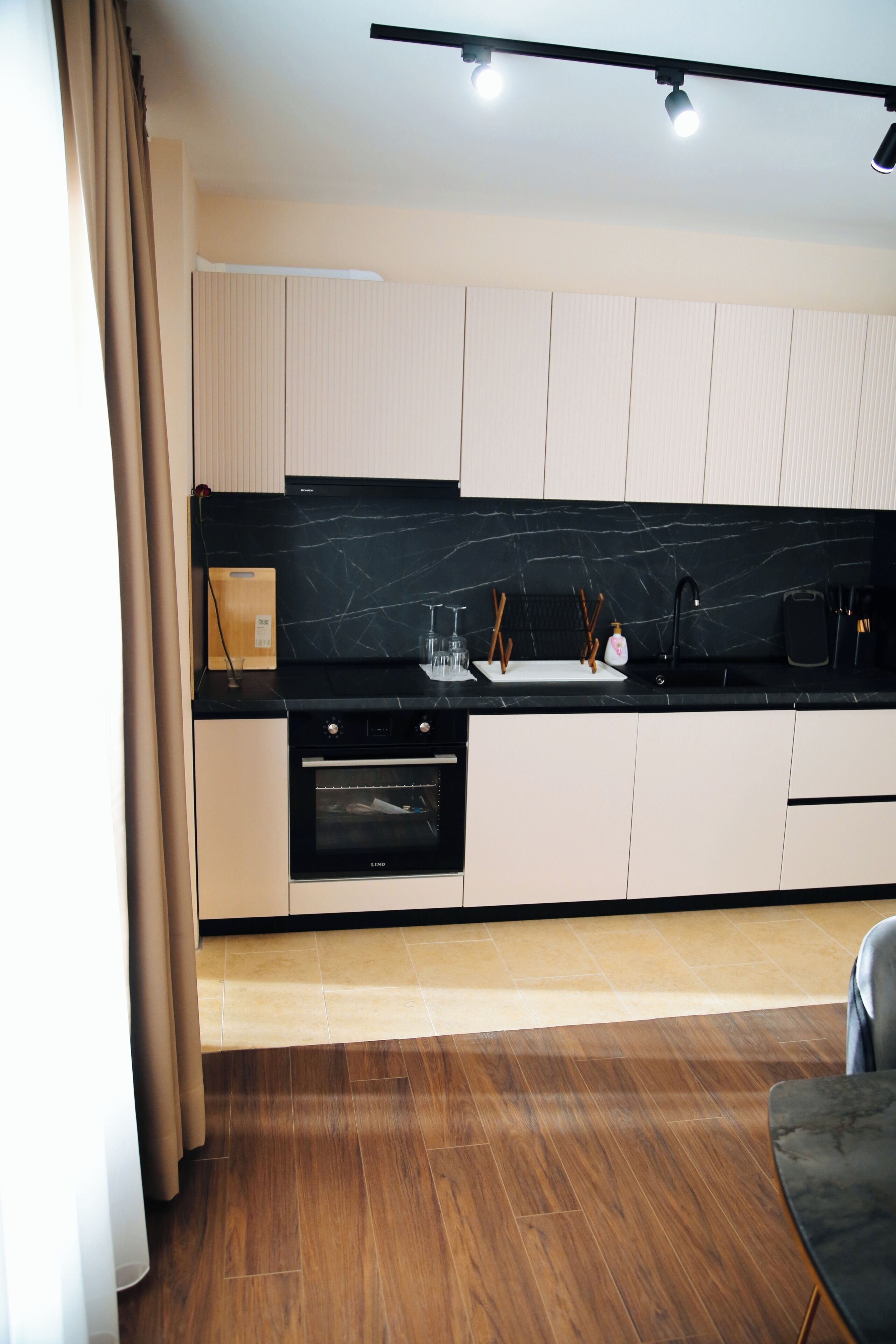 A modern kitchen with a black countertop, white cabinets, and a built-in oven.