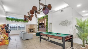 A recreational room with a pool table, a ceiling fan, a sofa, and a television. - Waterfront Jungle Home with Kayaks (Miami)