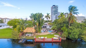 Zona residencial con piscina, muelle y construcción de techo de paja.