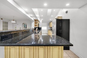 Eine moderne Küche mit einer großen Granitinsel, Edelstahlgeräten und hellen Holzschränken.