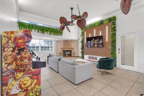 A modern living room with a fireplace, a sofa, a TV, and a decorative wall with plants. - Waterfront Jungle Home with Kayaks (Miami)