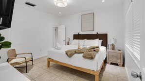 A hotel room with a bed, bedside tables, a chair, and a TV. - Waterfront Jungle Home with Kayaks (Miami)