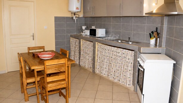 A compact kitchen with a dining table, chairs, a microwave, a sink, and a refrigerator. - 4-bedroom apartment near the beaches and attractions • Gated and secure residential community • The Beleric (Dakar)