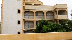 A multi-story building with a central tower, balconies, and a courtyard with greenery. - 4-bedroom apartment near the beaches and attractions • Gated and secure residential community • The Beleric (Dakar)