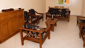 A living room with a sofa set, wooden side tables, and a cabinet. There are two wall-mounted air conditioning units and a window with a view of greenery. - 4-bedroom apartment near the beaches and attractions • Gated and secure residential community • The Beleric (Dakar)