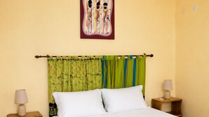 A bedroom with a bed, two nightstands, a wall-mounted painting, and curtains. - 4-bedroom apartment near the beaches and attractions • Gated and secure residential community • The Beleric (Dakar)