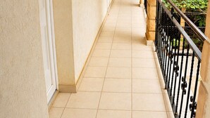 A corridor with tiled flooring, a white door, and a black metal railing. - 4-bedroom apartment near the beaches and attractions • Gated and secure residential community • The Beleric (Dakar)
