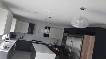 A modern kitchen with a marble floor, stainless steel appliances, and pendant lighting.
