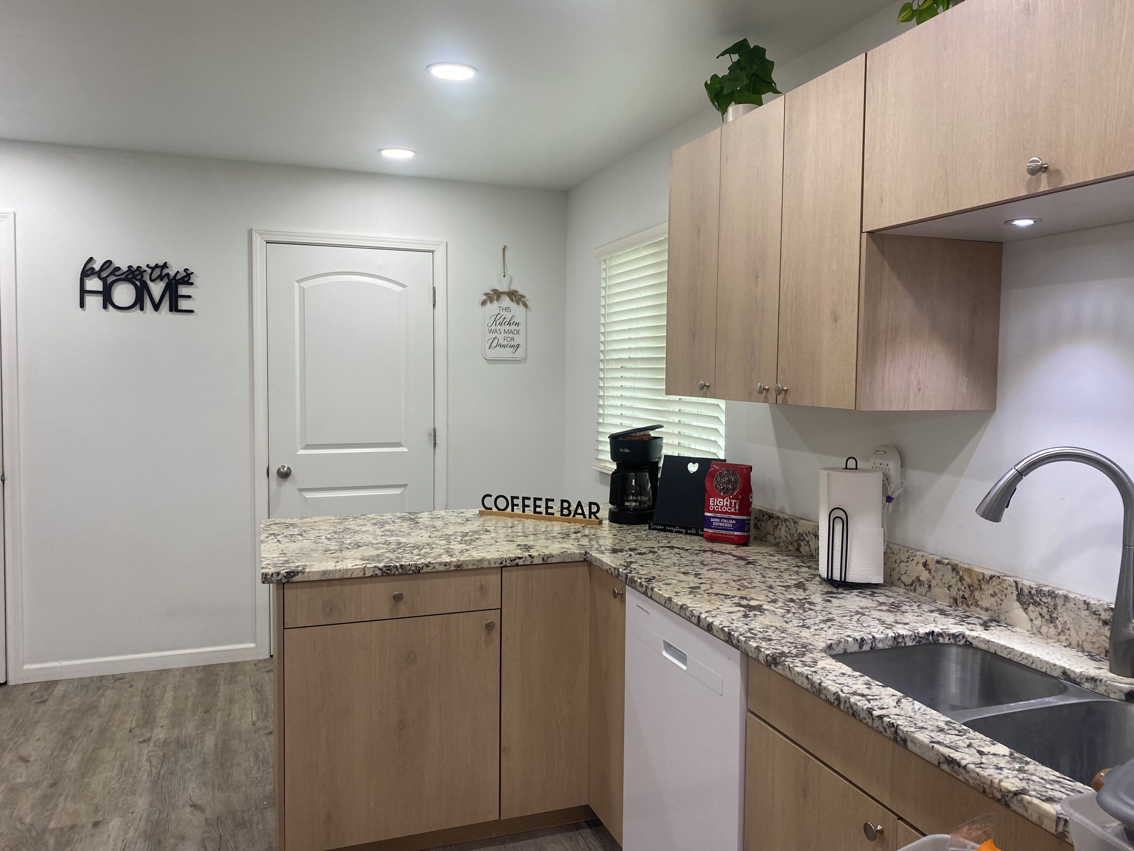 A kitchen with wooden cabinets, a granite countertop, a coffee bar, and a sink.