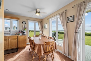 A kitchen with a dining area, large windows, and a view of the outdoors.