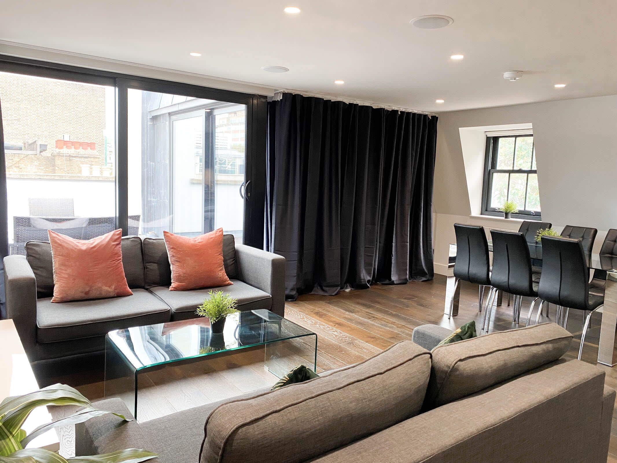 Un salon moderne avec un canapé, une table basse en verre et un coin repas avec des chaises.