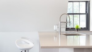 Uma cozinha moderna com uma ilha grande, uma janela com vista e dois bancos altos.