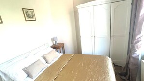 A bedroom with a bed, a wardrobe, and a nightstand. - Stylish Central London apartment is next to the tube Chelsea border (London)
