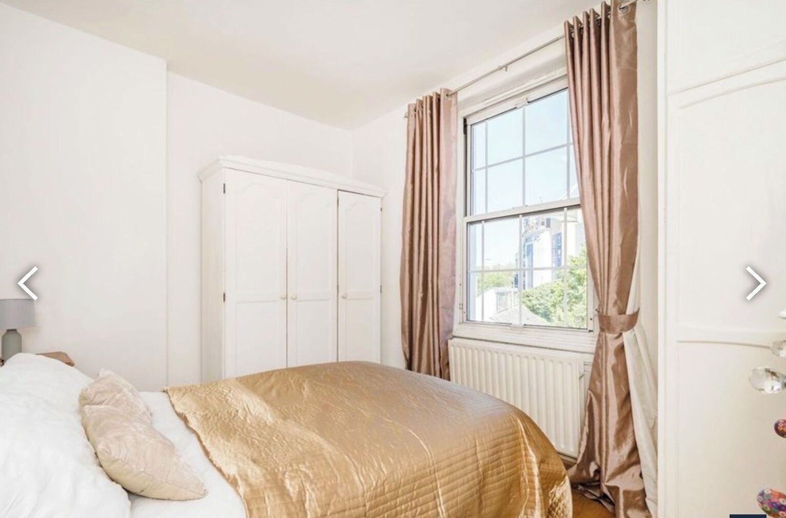 A bedroom with a bed, a wardrobe, and a window with curtains.