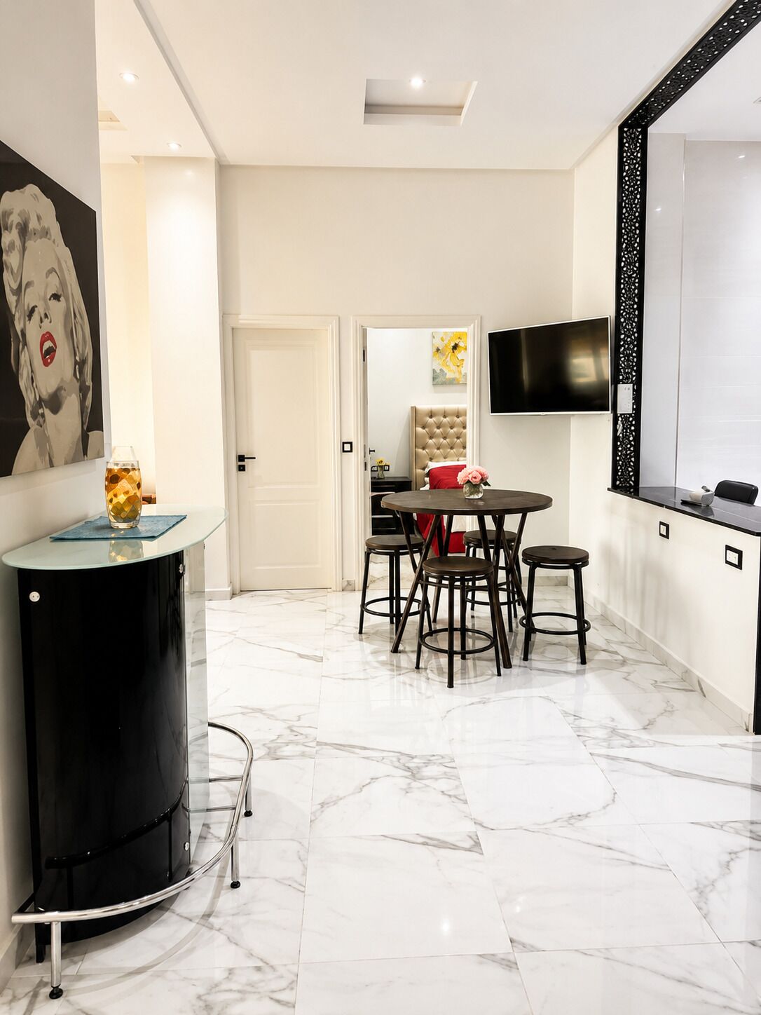 Cocina moderna con comedor, piso de mármol y televisor montado en la pared.