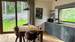 A modern kitchen with a large island, wooden flooring, and a view of a forested area. - Nice apartment for 5 guests with WIFI, TV and balcony (Jilemnice)