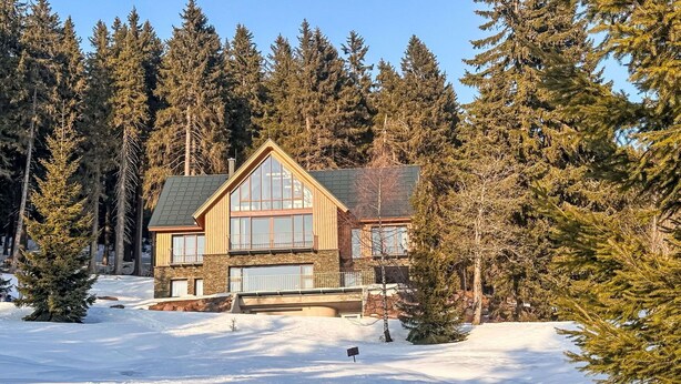 A log cabin with a large front porch, surrounded by snow and evergreen trees. - Nice apartment for 5 guests with WIFI, TV and balcony (Jilemnice)