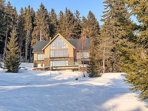 A log cabin with a large front porch, surrounded by snow and evergreen trees. - Cosy apartment for 5 guests with WIFI, TV and balcony (Jilemnice)