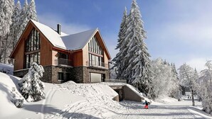 A two-story wooden lodge with a ski slope in the foreground. - Nice apartment for 5 guests with WIFI, TV and balcony (Jilemnice)