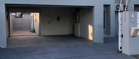 Ein modernes Gebäude mit einer Garageneinfahrt, einem gepflasterten Auffahrt und einem befestigten Bereich mit einer Hinweisschild.