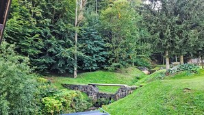 Uma paisagem verdejante e exuberante com uma ponte de pedra e árvores densas.
