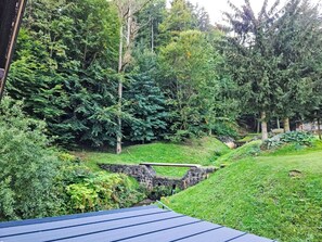 Üppige grüne Landschaft mit einer Steinbrücke und dichten Bäumen.