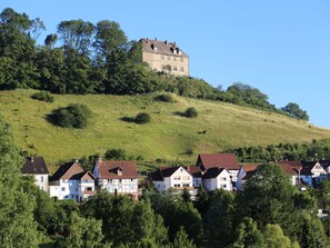 Un castillo en la cima de una colina con vistas a una zona residencial con casas tradicionales.