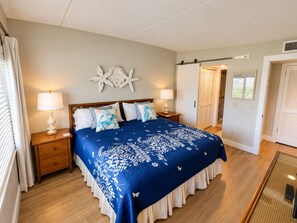 Una camera da letto con un letto, due comodini con lampade, un elemento decorativo a parete e una porta che dà su un'altra stanza.