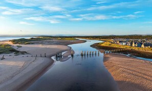 Eine Küstenlandschaft mit einem Fluss, Sandstrand und einer Ansammlung von Gebäuden.