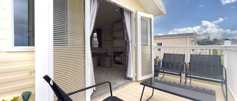 A balcony with a table and chairs, a sliding glass door leading to an interior space, and a view of the surrounding area.