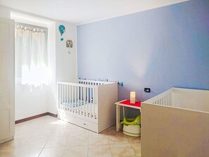 Een kamer met een wiegje, een klein tafeltje met een rode blad en een muur met blauwe accenten.