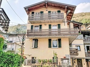 Ein mehrstöckiges Gebäude mit Balkonen, einer flachen Dachterrasse und einer Bergkulisse.