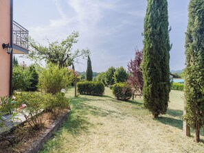 Un jardín bien cuidado con diversos arbustos y un alto árbol de hoja perenne.