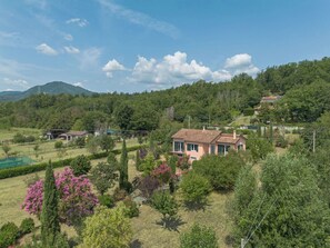 A residential area with houses surrounded by greenery and a mountainous backdrop.