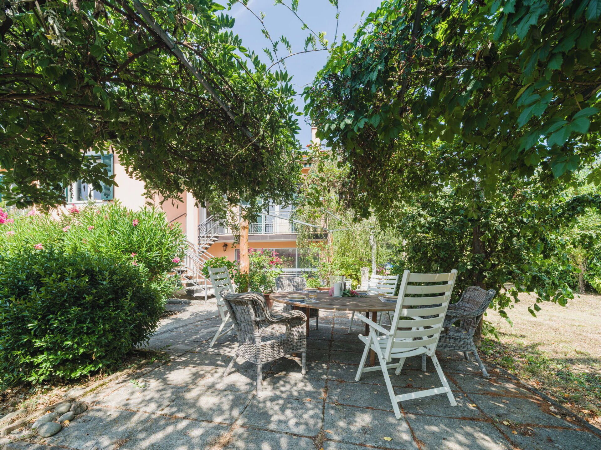 An outdoor patio with stone flooring, wicker furniture, and a view of a building in the background.