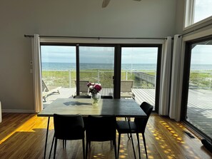 Et værelse med en stor skydedør, der fører til en terrasse med havudsigt.