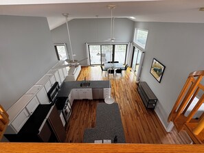 A modern kitchen with a dining area, wooden flooring, and large windows.