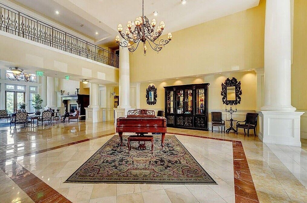 Un vaste hall d’entrée agrémenté d’un piano, de lustres et doté d’un plafond haut.
