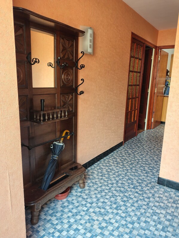 A hallway with a wooden door, a wall-mounted light switch, and a tiled floor. - 600 meters from the beach, a former farmhouse that sleeps 5; pets allowed. (Erquy)