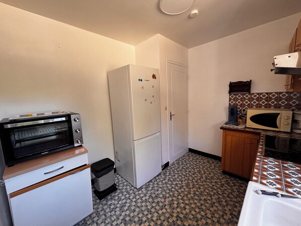 A compact kitchen with a built-in oven, a refrigerator, a microwave, and a sink.