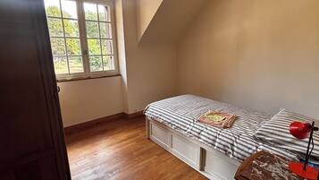 Een slaapkamer met een bed, een raam en een houten vloer.