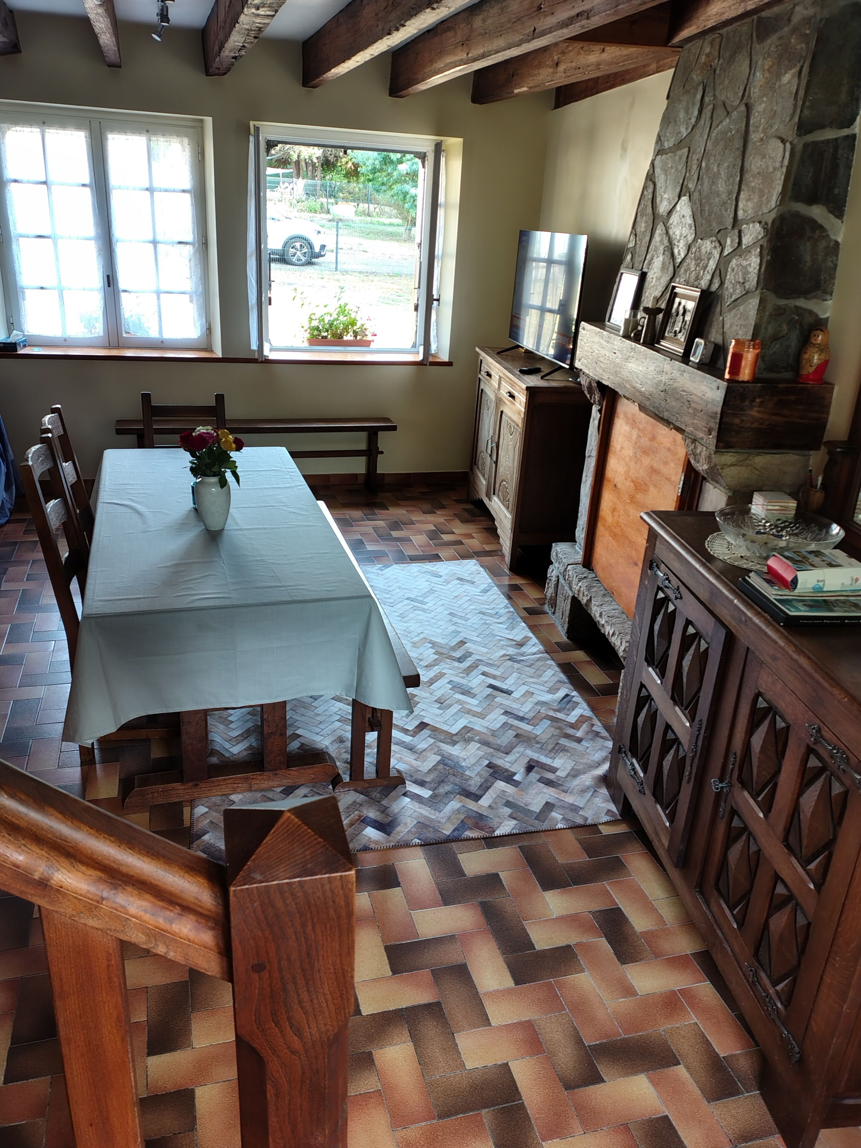 Een eetgedeelte met een tafel, stoelen, een bank, een stenen openhaard en uitzicht op de omgeving.
