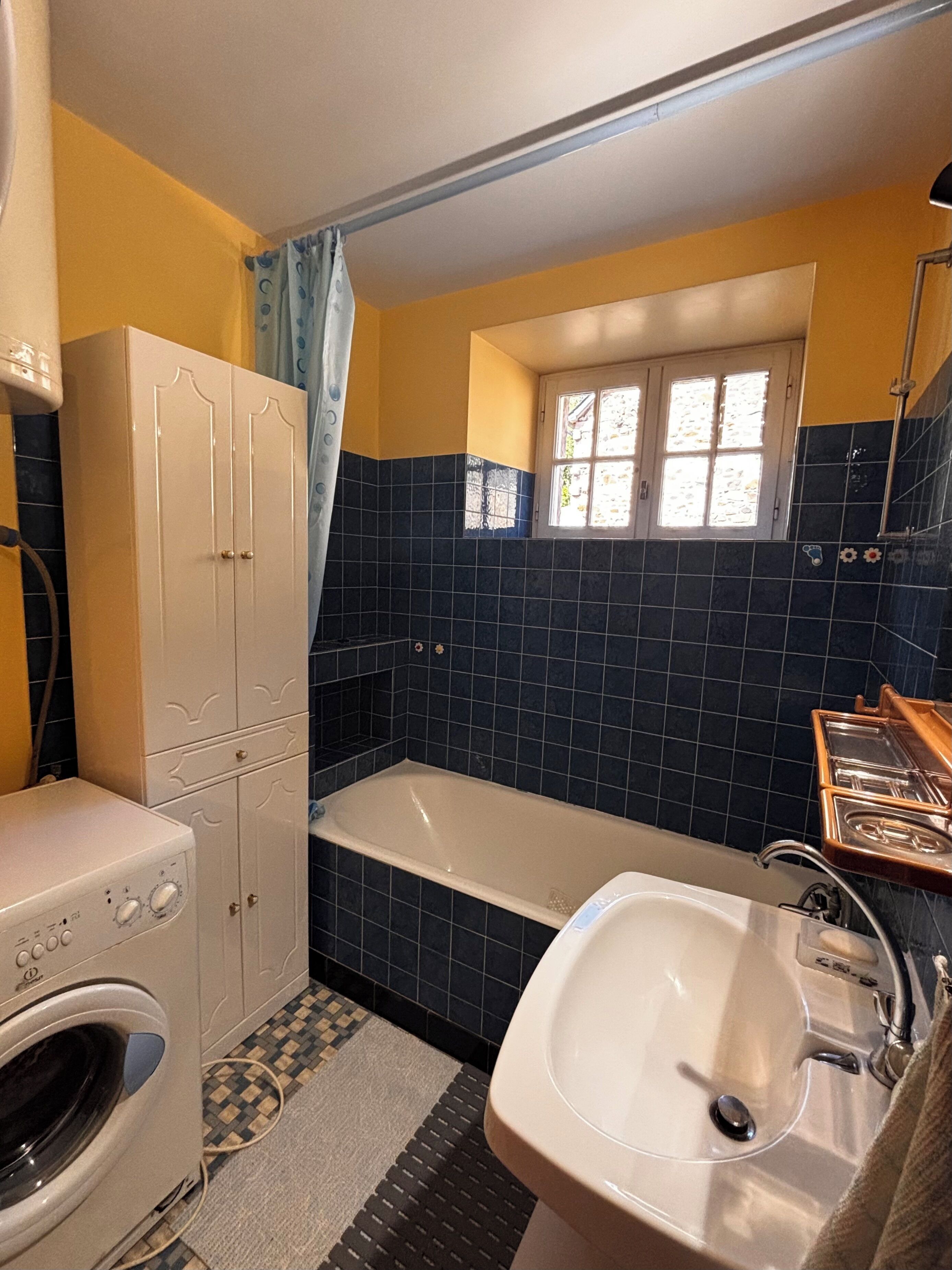 Ein Badezimmer mit einer Badewanne, einem Waschbecken und einer Waschmaschine.