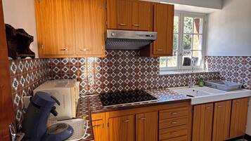 Een keuken met houten kastjes, een ingebouwde kookplaat en een betegelde spatwand.
