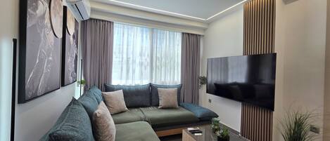 A modern living room with a sectional sofa, a flat-screen TV, and a coffee table.