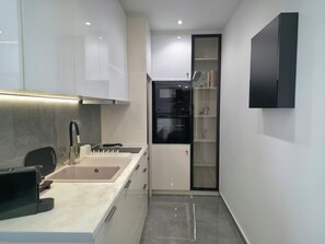 Een moderne keuken met een inbouwoven, een spoelbak en een zwart aanrecht.
