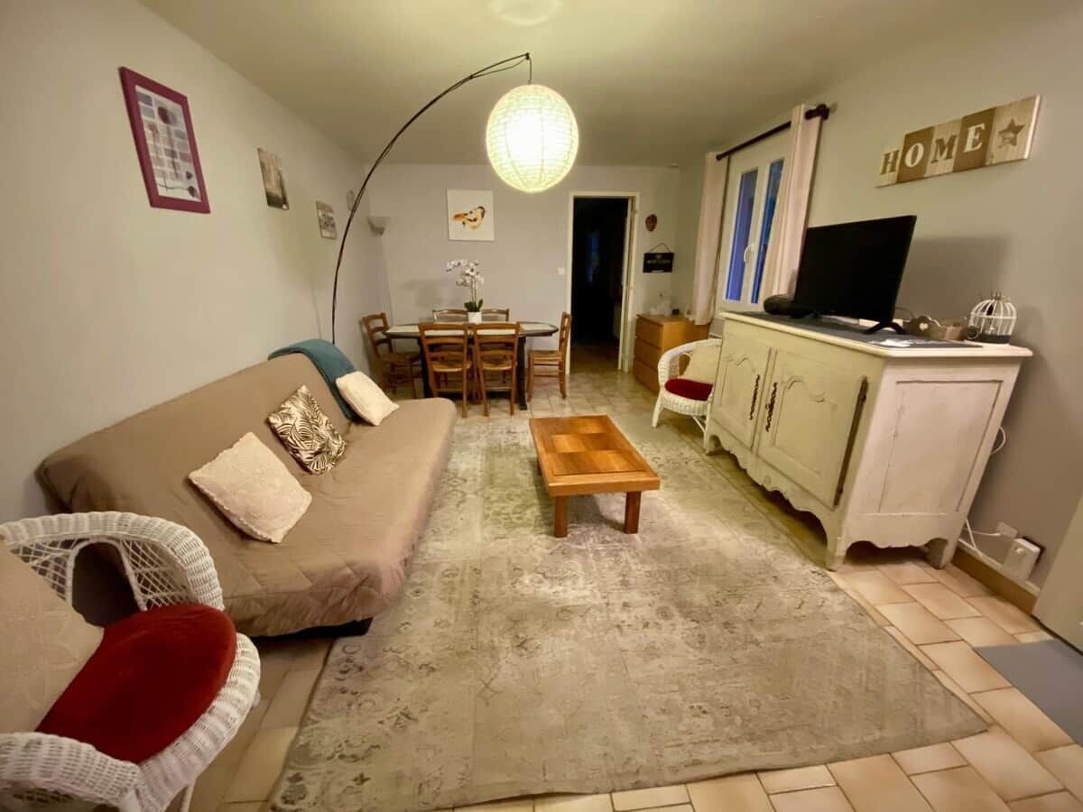 A living room with a sofa, a coffee table, a dining table with chairs, a TV, and a cabinet.